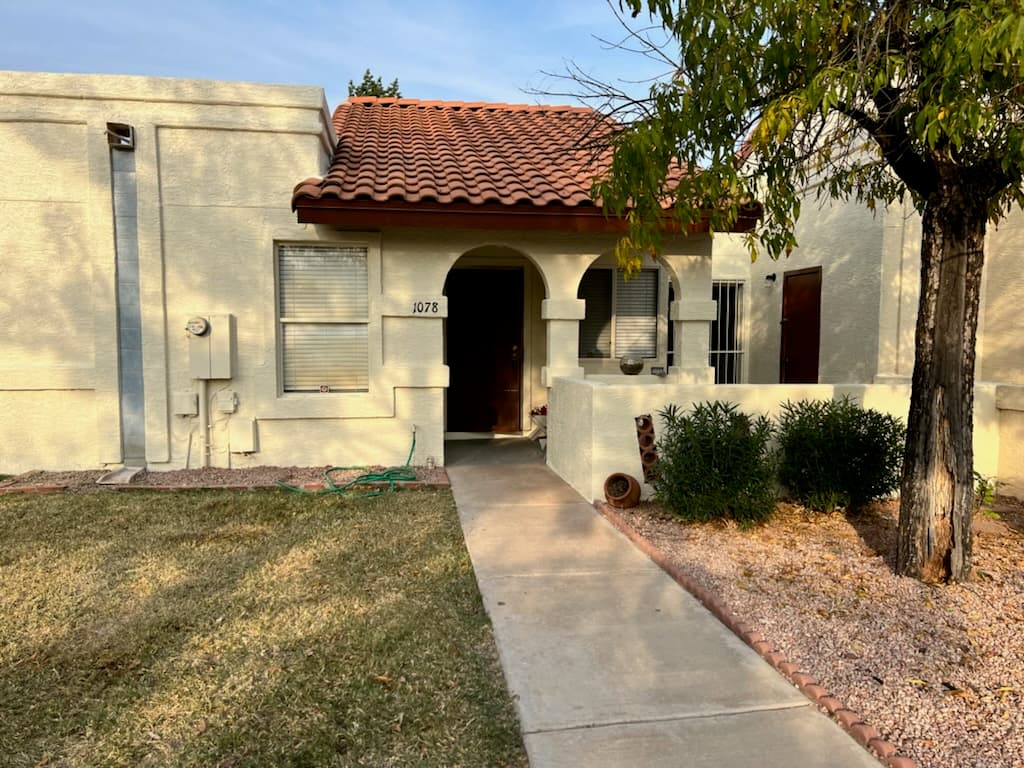 A single-story cream stucco home with a red tile roof, freshly painted trim and entry