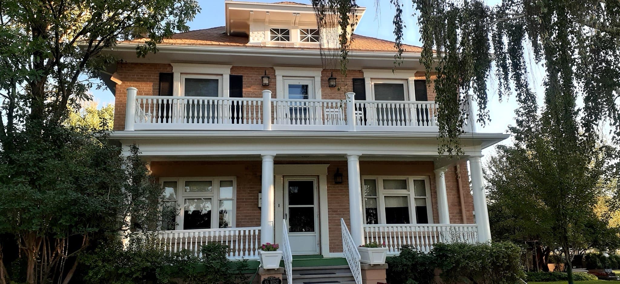 The same historic home with crisp white columns, balustrade and trim against exposed brick