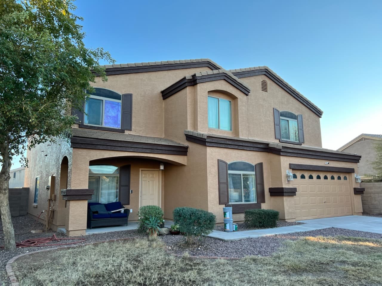 Two-story stucco home with dark brown trim and shutters