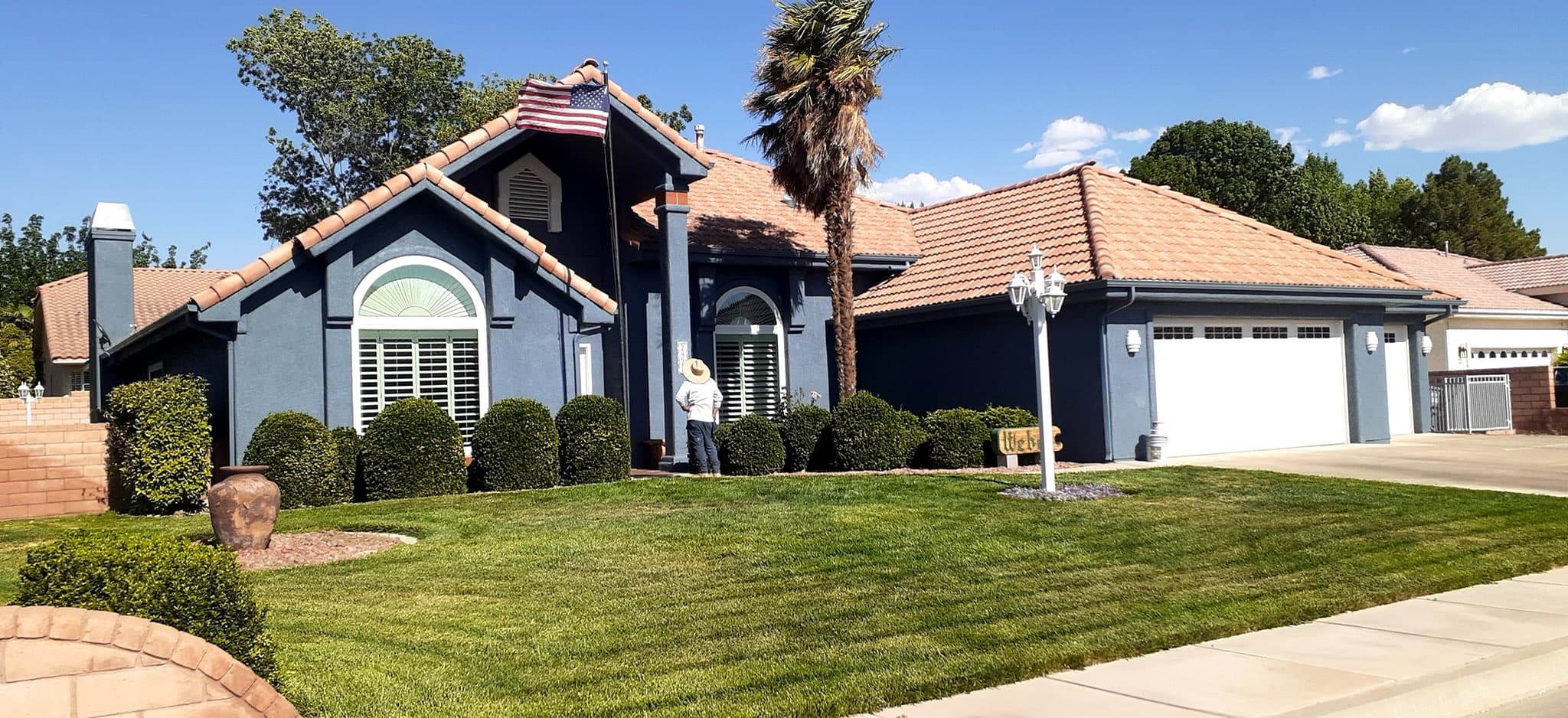 A single-story ranch home painted deep slate blue with white trim under a tile roof