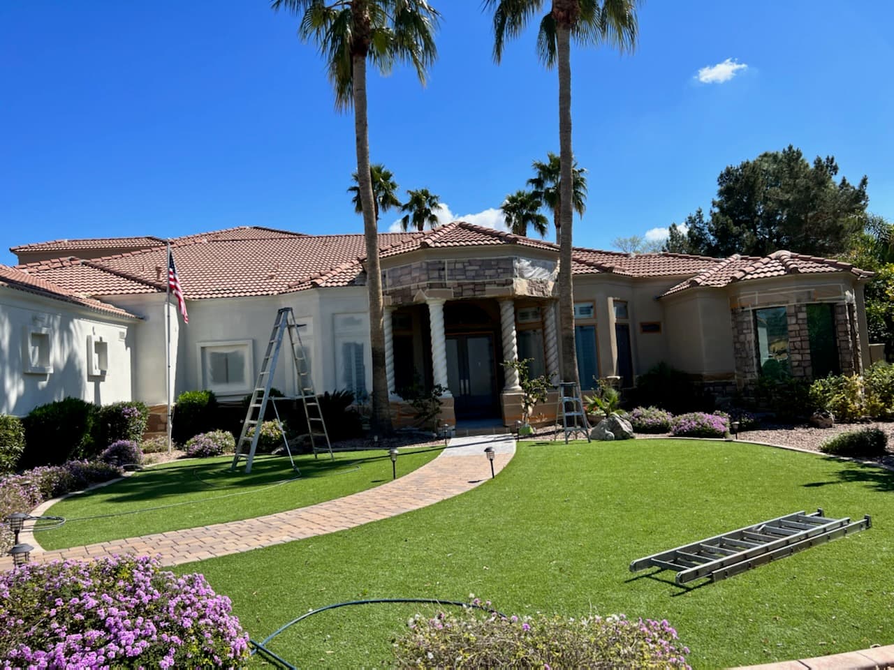 Large estate home with ladders set up and the stone entry masked off