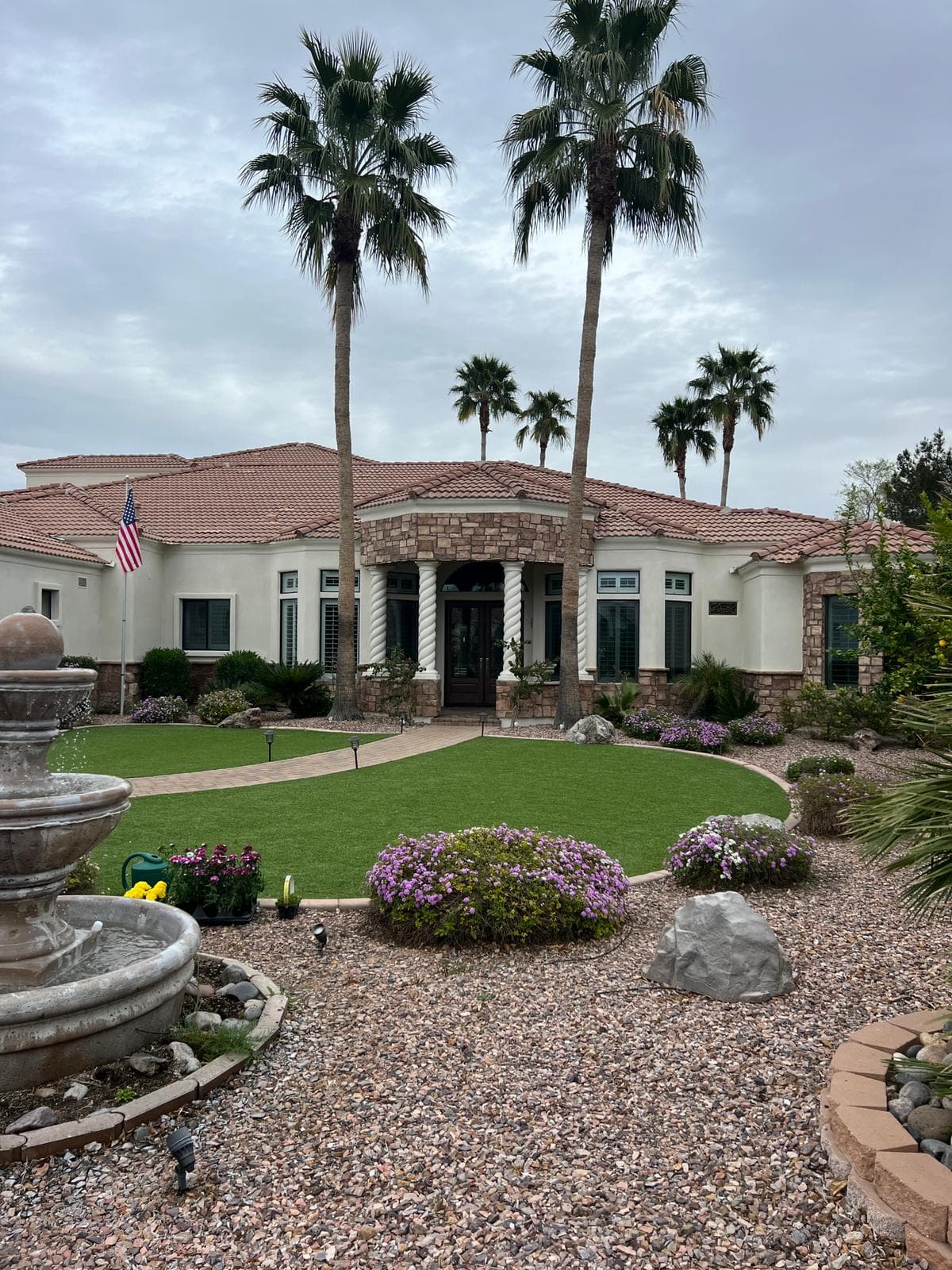 A large repainted home seen across the front fountain and lawn